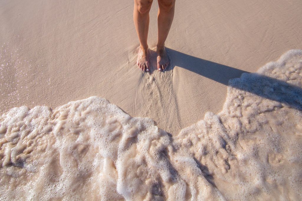 womans feet in sand with waves 4460x4460